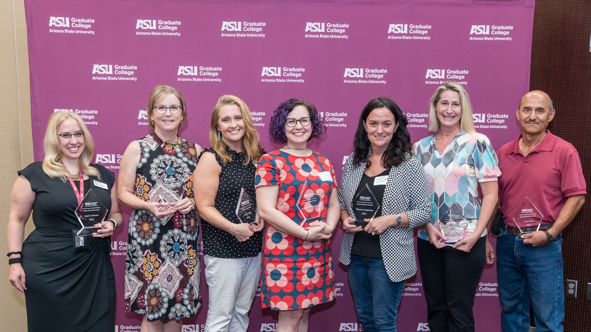 Seven of the ten winners of the Graduate College Awards for Excellence smile holding up their award plaques