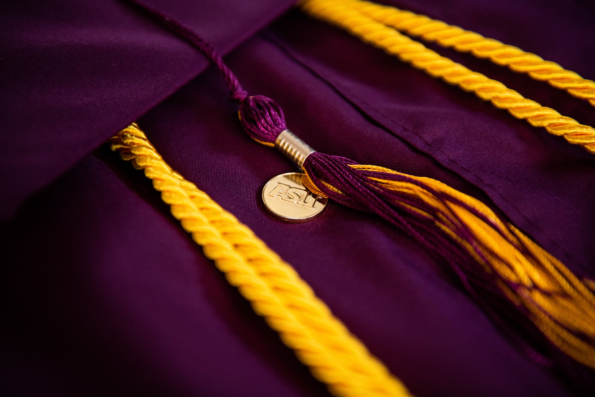 commencement regalia, maroon robes and "asu" gold charm on tassel