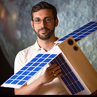 Craig Hardgrove holding the shoebox-sized satellite CubeSat.