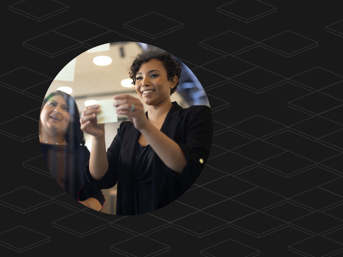 Two graduate students smiling and using sticky notes to collaborate