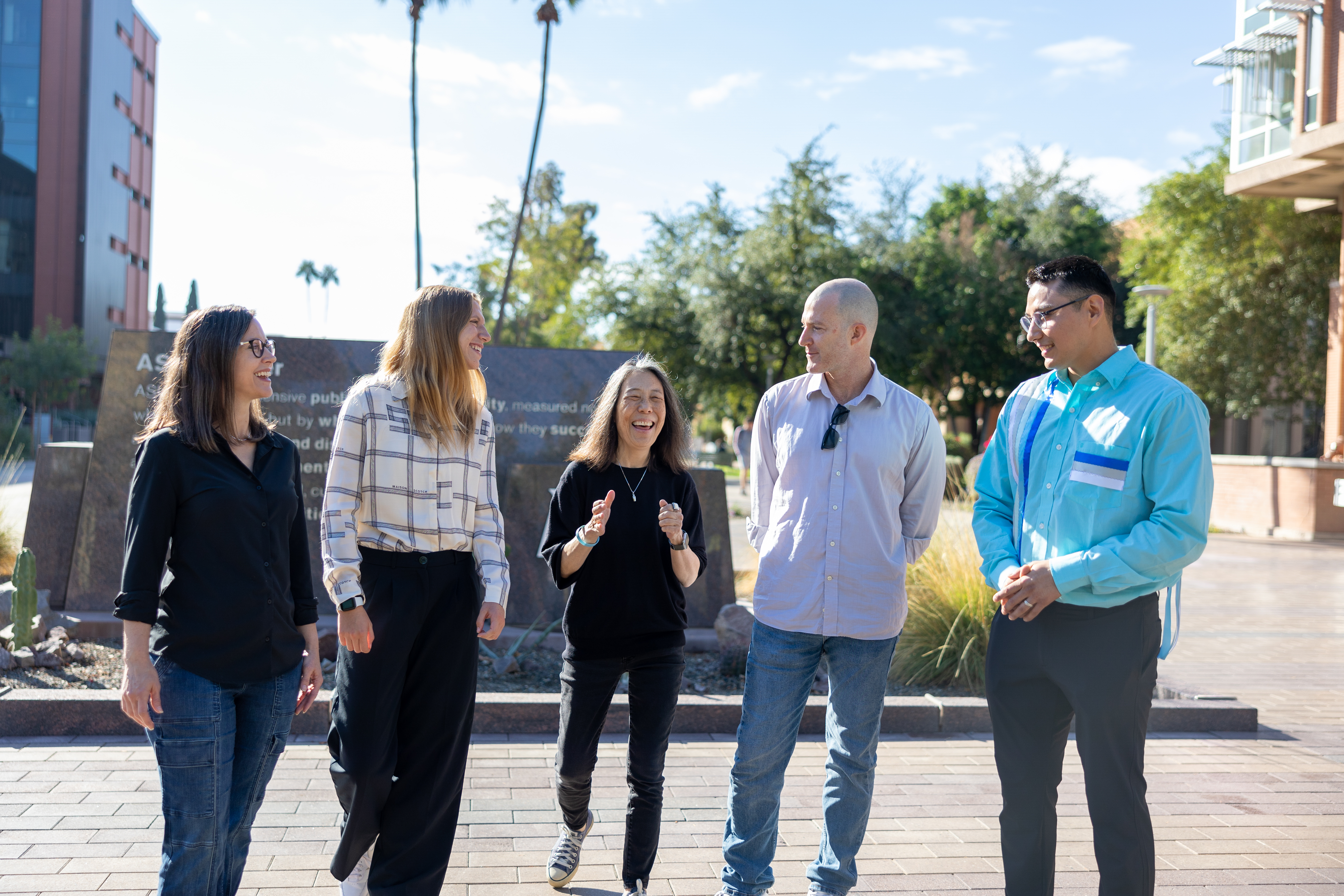 Group of graduate students and faculty walking in front of ASU Charter stone